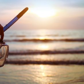 silhouette of woman hand with mask and snorkel about to go Maui snorkeling