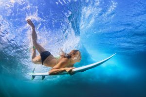 Beautiful surfer girl diving under water with surf board - things to do Maui