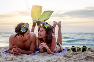 Young Asian happy couple with snorkels and lying on the beach at sunset, Maui Snorkeling