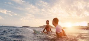 Fit couple surfing at sunset with maui eco tours-