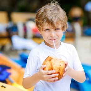 Young boy sipping from a coconut and enjoying the things to do on Maui with kids