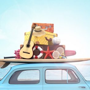 little blue car packed with surf board, guitar and suitcases in front of the ocean for Maui Spring Break