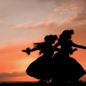 Maui women dancer figures against orange sunset backdrop at a Maui Luau