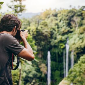 Male hiker photographing a west Maui waterfall in forest