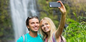 Couple finding the perfect maui selfie spot in front of a waterfall and snapping a picture