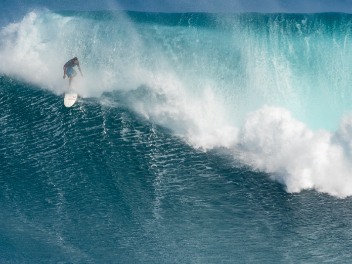 surfer riding big wave at jaws surf break